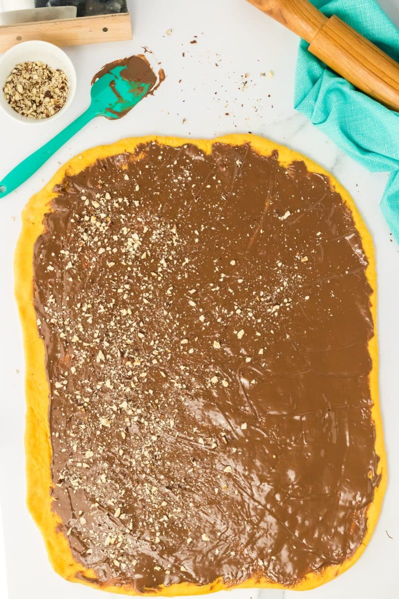 Rolled pumpkin yeast bread dough topped with chocolate nutella hazelnut filling - Hostess At Heart