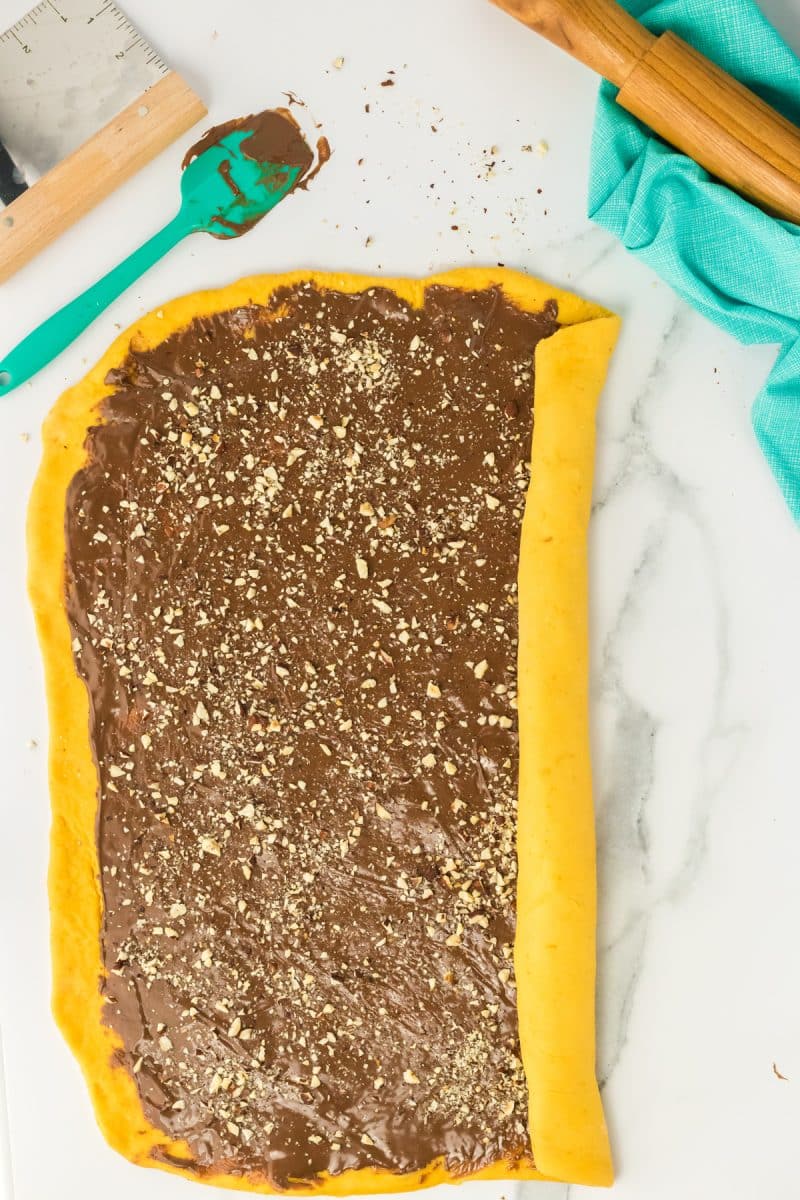Chocolate nutella and chopped hazelnut filling rolled into a long log of pumpkin yeast bread dough - Hostess At Heart