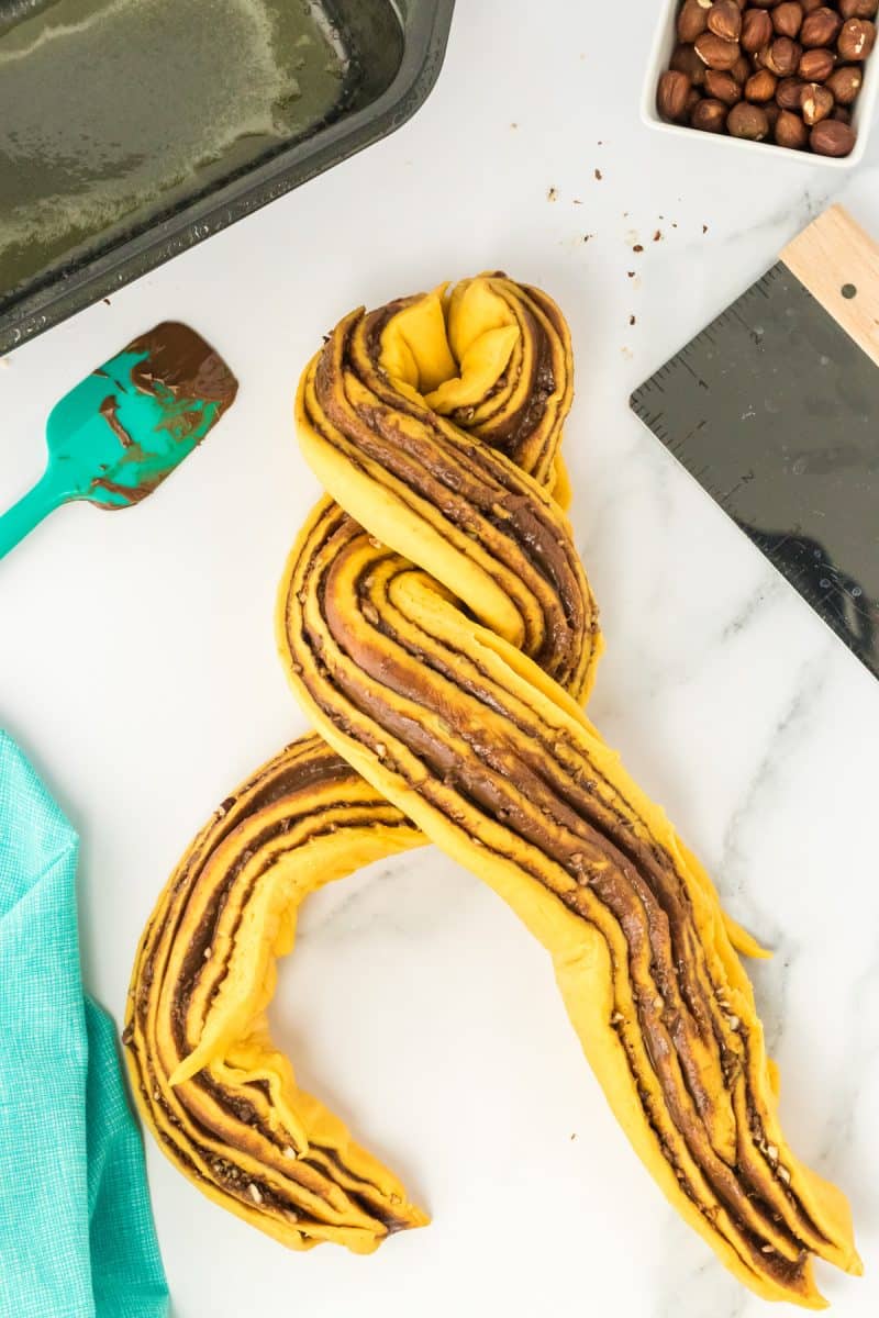 Rolled pumpkin babka bread that's been sliced and is now being twisted with the filled sides up.