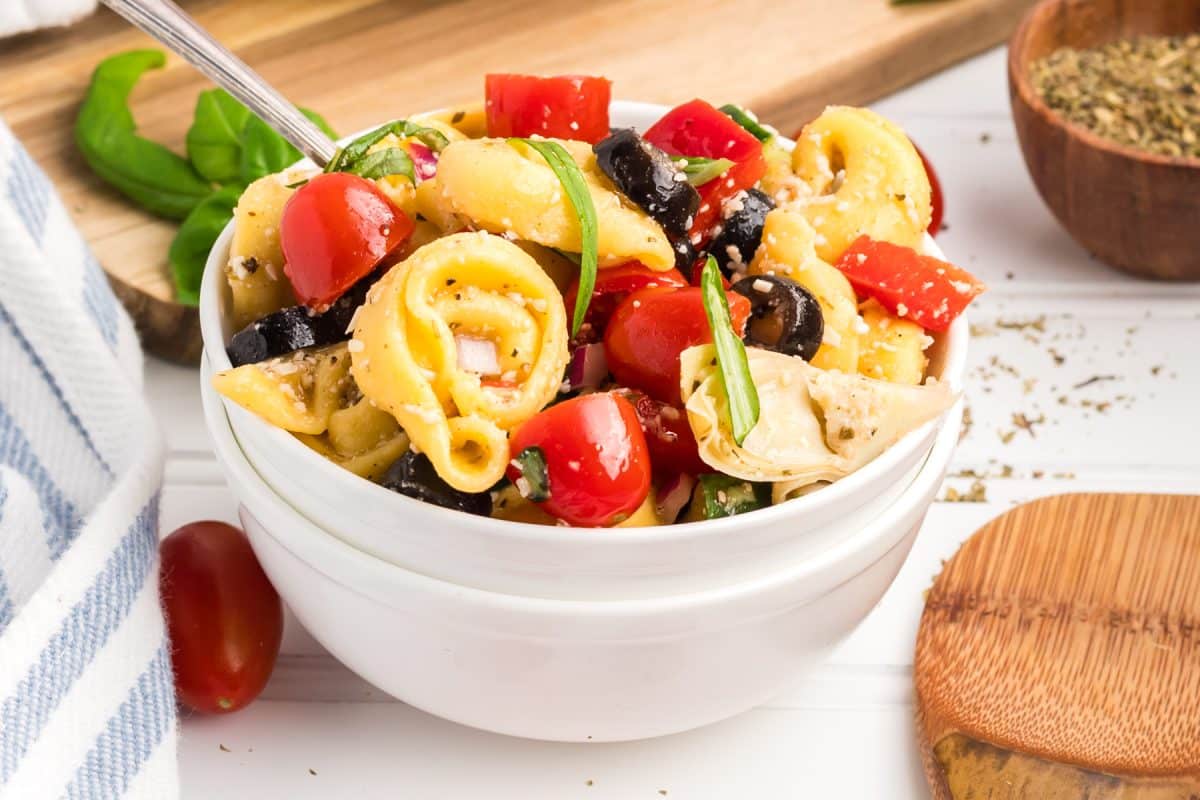 A bowl filled with a pasta salad made with cheesy tortellini made with herbs and dfresh veggies - Hostess At Heart