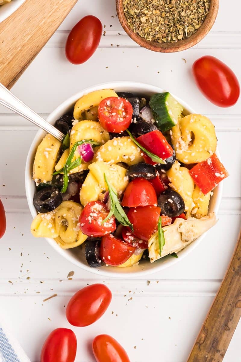 Angled view of a bowl filled with a colorful tortellini salad mixed with freshly chopped vegetables - hostess at heart