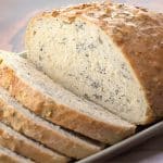 A tableview of a sliced loaf of pumpernickle bread infused with seeds and grains - Hostess At Heart