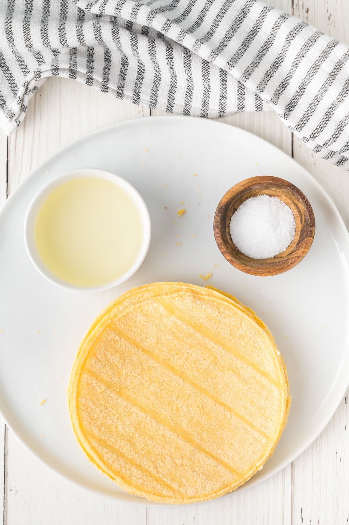Top down view of ingredients used to make homemade corn tortilla chips including corn tortilla shells, salt, and vegetable oil - Hostess At Heart