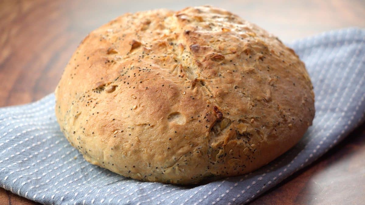 A sideview of a beautiful golden brown loaf of pumpernickel bread - Hostess At Heart