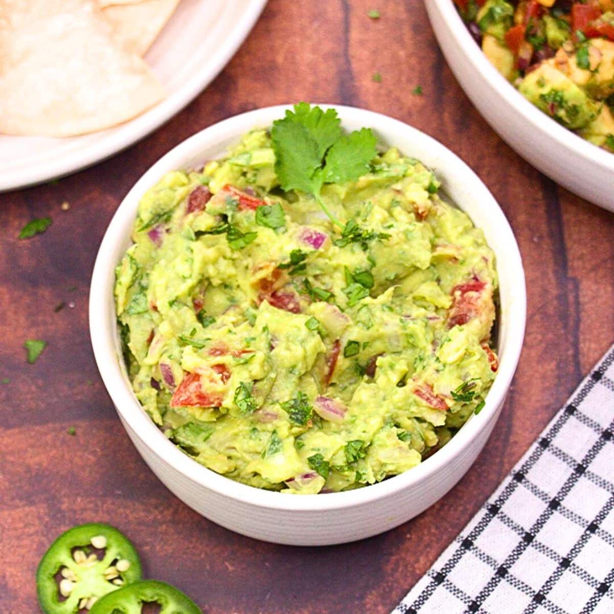 A bowl of fresh homemade guacamole loaded with chunky avocado, tomato, red onion and cilantro - Hostess At Heart