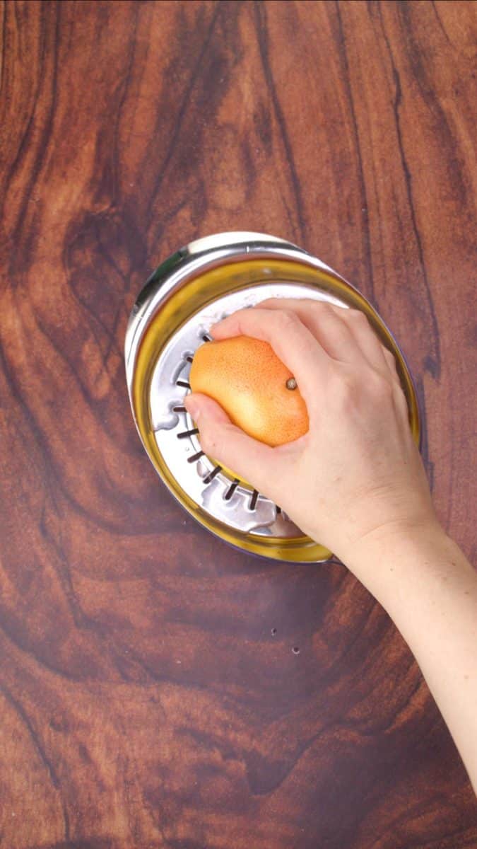 A hand juicing a grapefruit into a container - Hostess At Heart