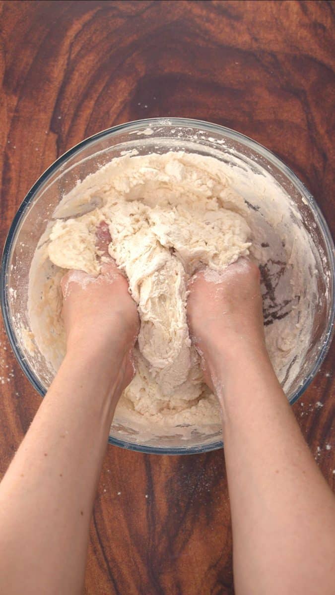 Two hands mixing up bread dough with pumpernickel flour - Hostess At Heart