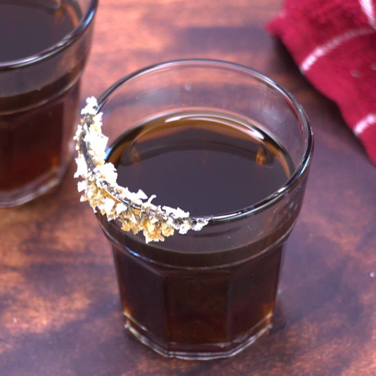 An image of a dark salted caramel bourbon cocktail with a salted caramel rim. Hostess At Heart