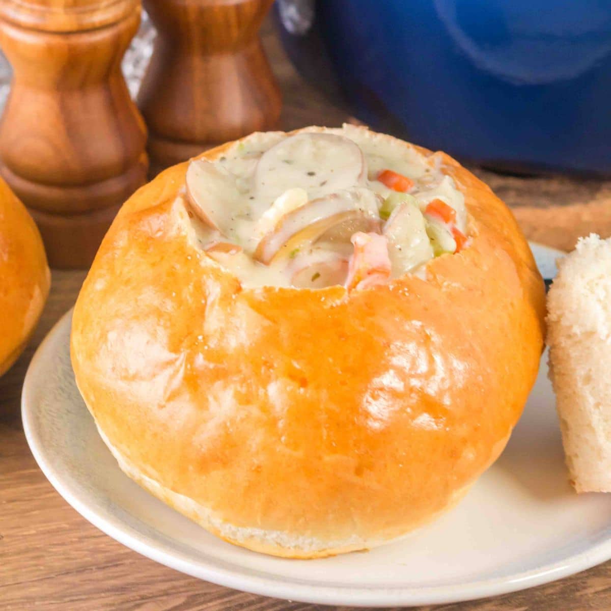 A bread bowl filled with clam chowder soup. The wedge removed from th boule is propped up to the side - Hostess At Heart
