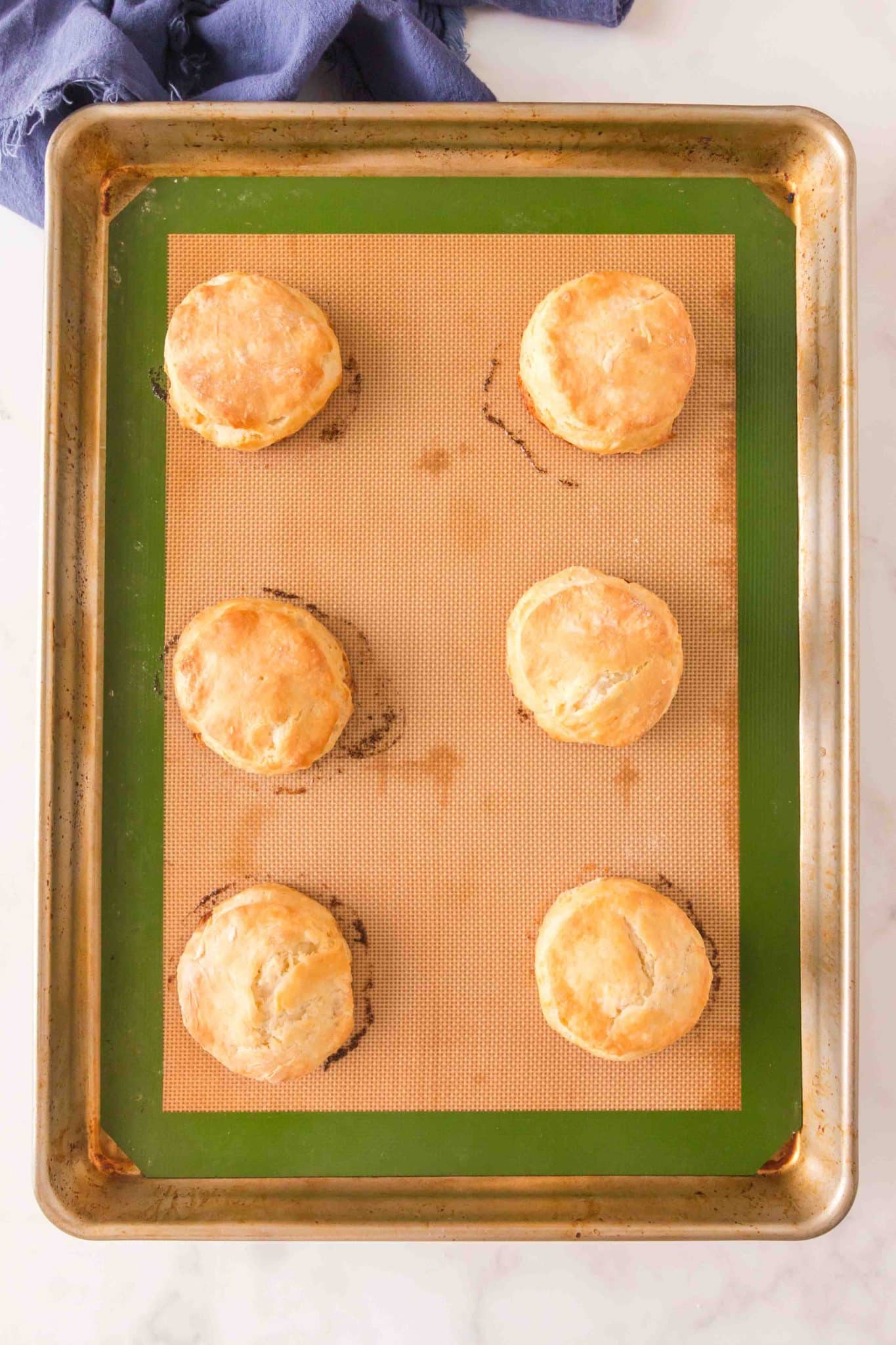 Top down view of baked sourdough biscuits on a silicone mat. Hostess At Heart