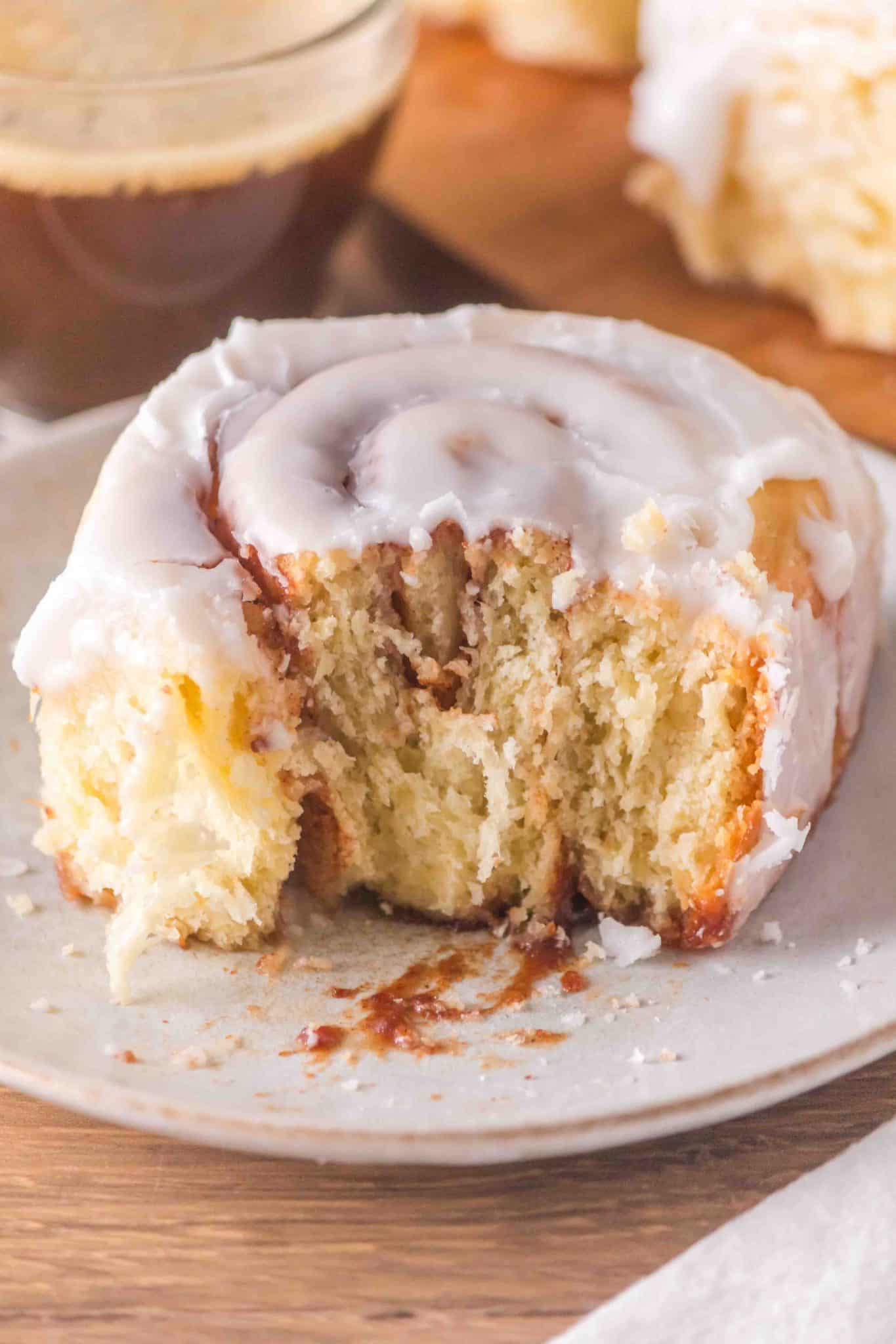 A freshly baked overnight sourdough cinnamon roll with the front pulled off showing swirls of cinnamon and a soft tender roll - Hostess At Heart
