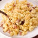 Closeup angled view of a spoon filled with creamy mac and cheese with bacon - Hostess At Heart