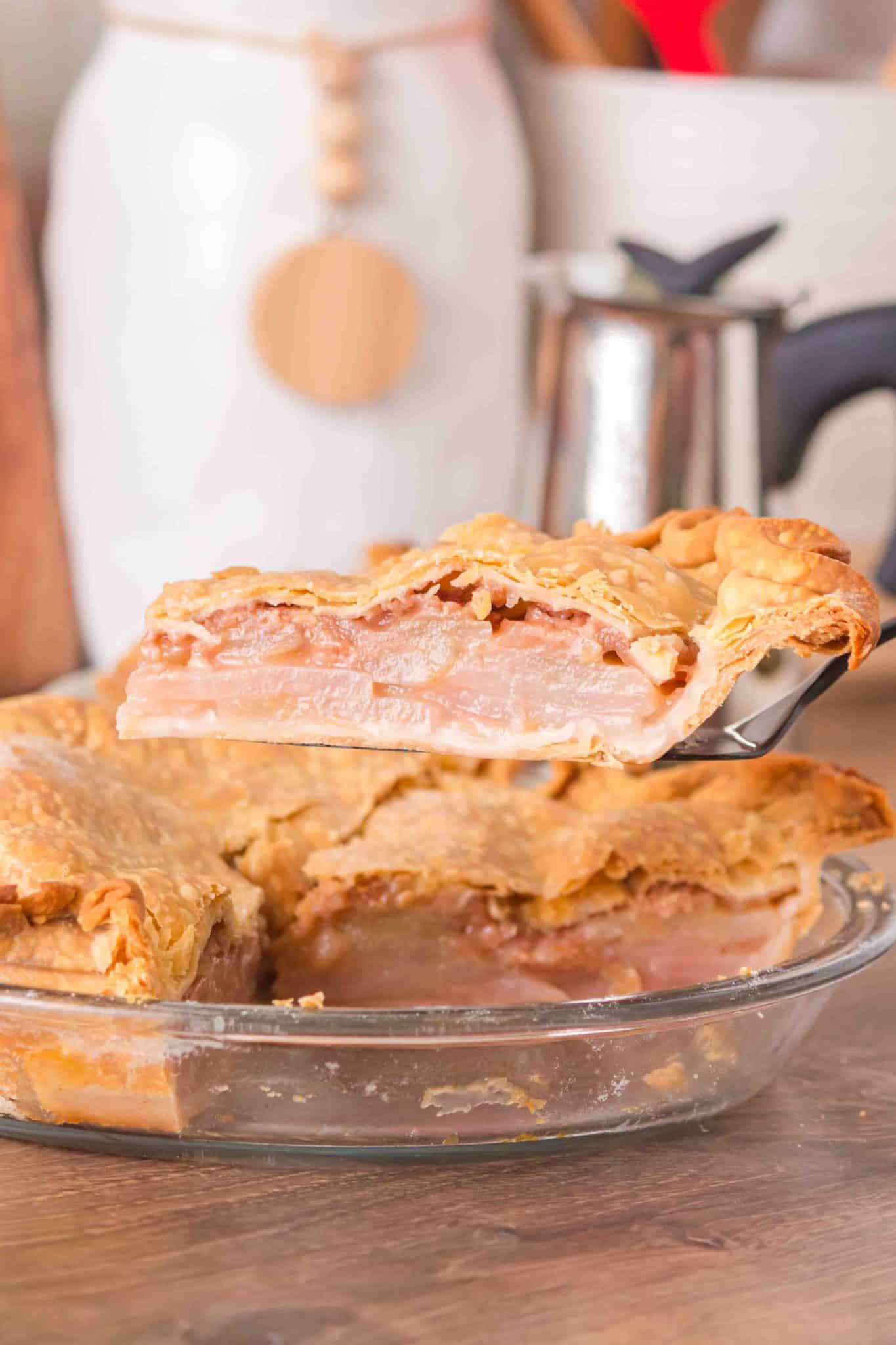 Sideview of a slice of pear pie on a spatula hovering over the pie pan - Hostess At Heart