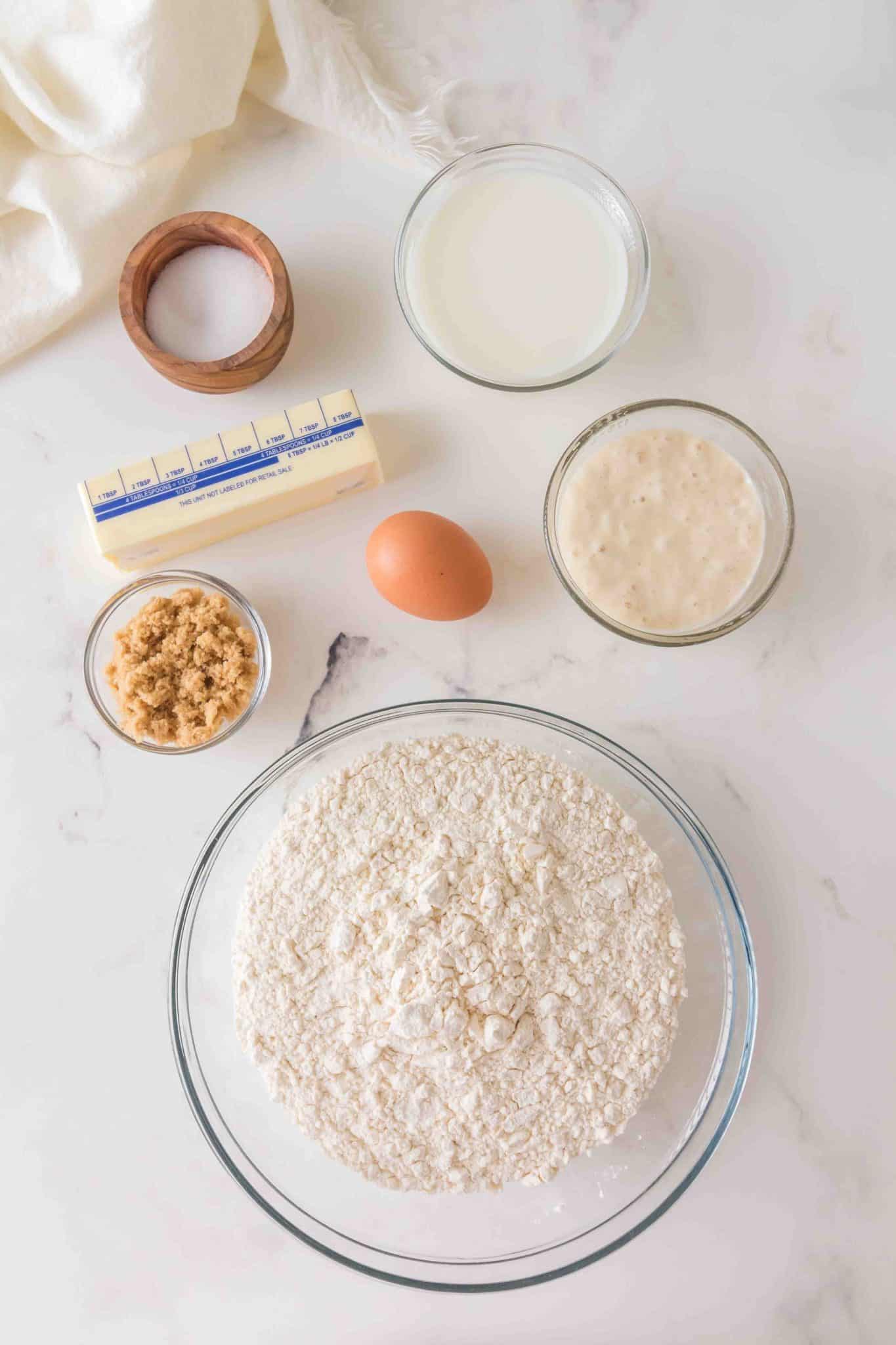 Sourdough cinnamon roll ingredients: flour, cinnamon, milk, egg, brown sugar, butter, sourdough starter, and salt. Hostess At Heart