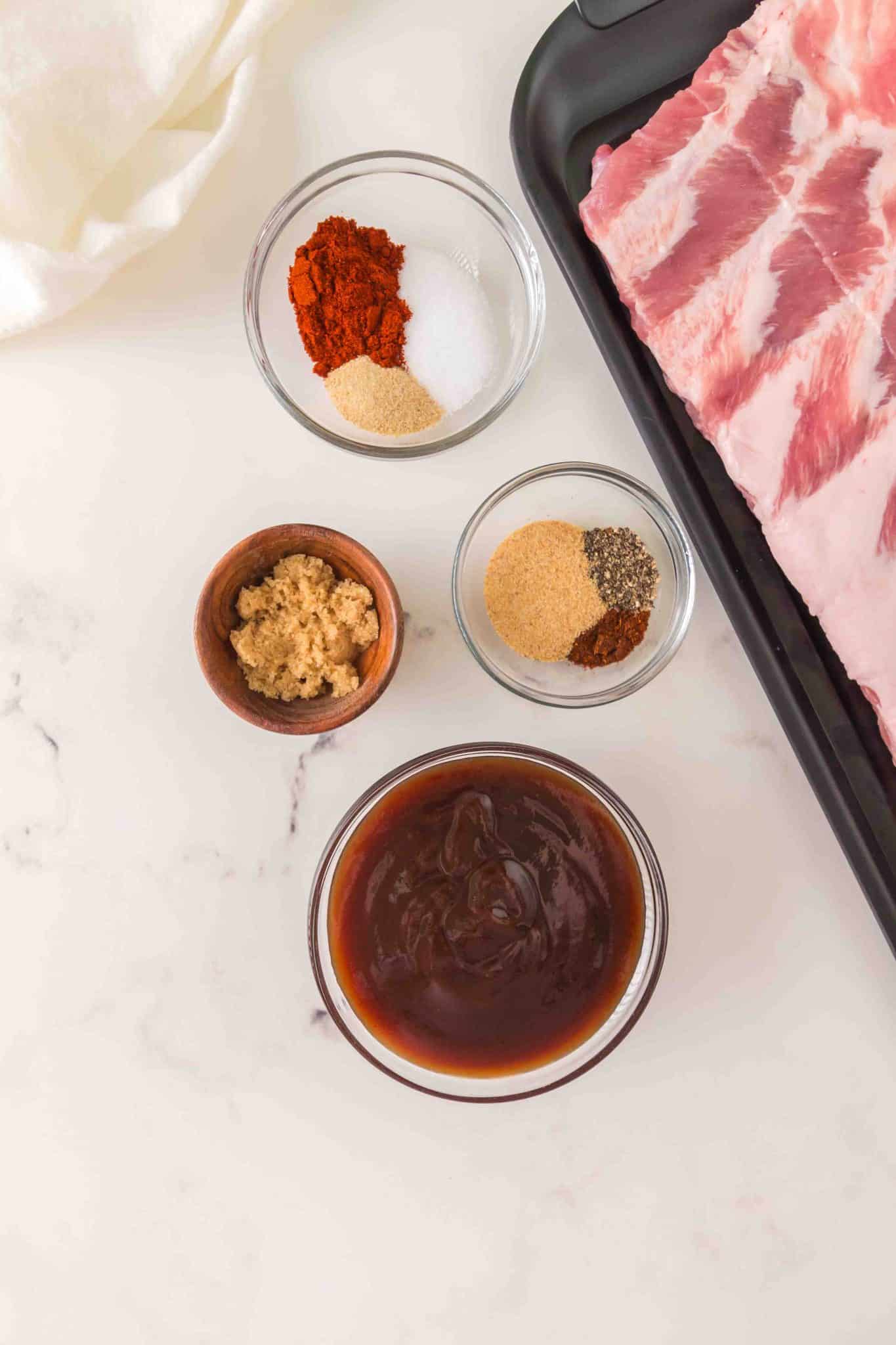 BBQ baby back rib ingredients: baby back rib rack, bbq sauce, brown sugar, and spices - Hostess At Heart