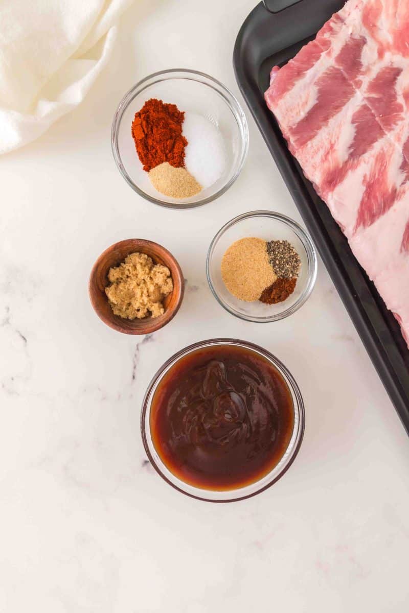 BBQ baby back rib ingredients: baby back rib rack, bbq sauce, brown sugar, and spices - Hostess At Heart