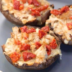 Closeup angled view of a crab stuffed portobello mushroom topped with sundried tomatoes - Hostess At Heart