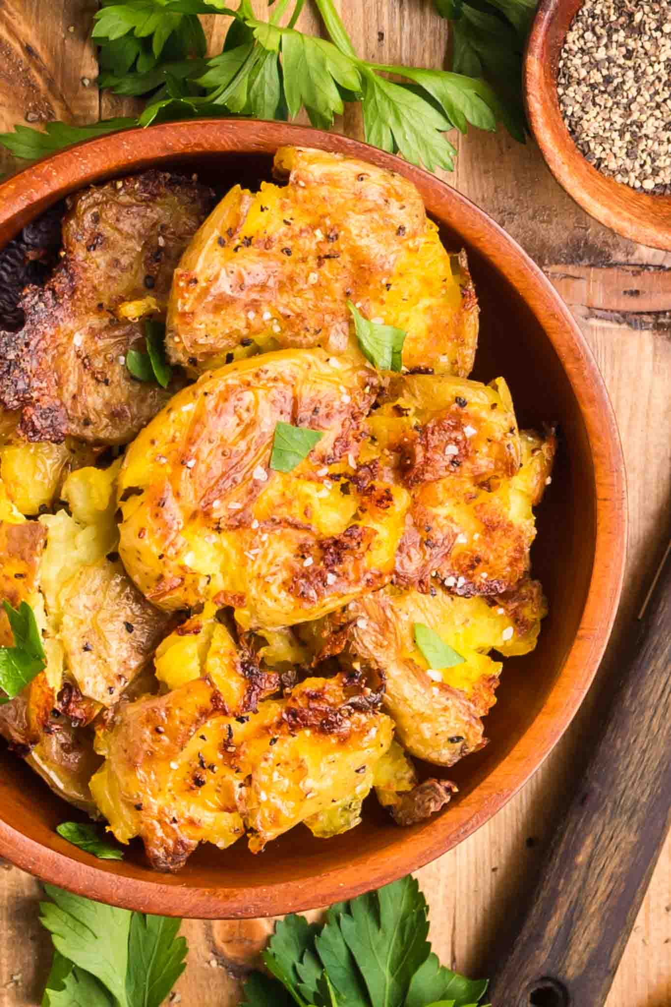 Top down view of crispy golden brown smashed parmesan potatoes in a bowl - Hostess At Heart