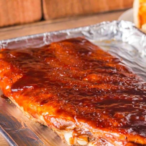 Angled view of bbq sauce slathered on a rack of baked ribs - Hostess At Heart