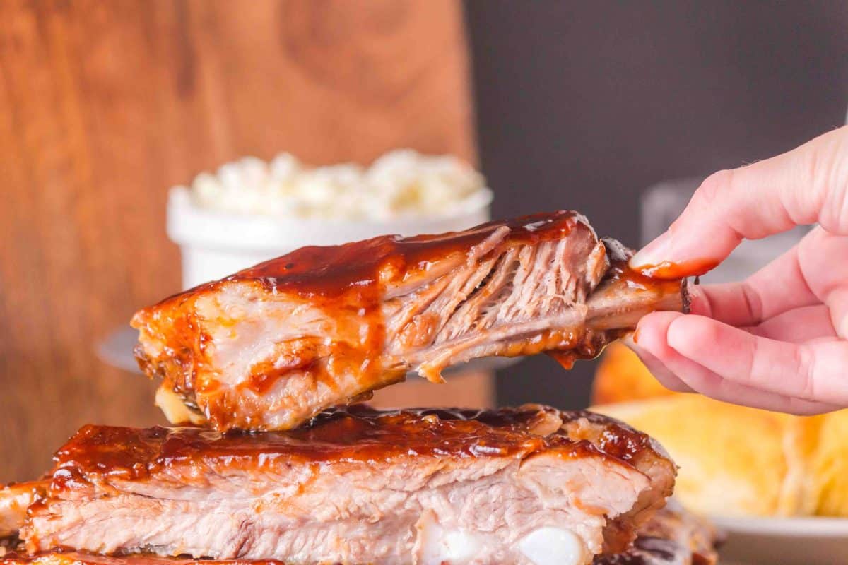A hand holding a saucy BBQ Pork Rib - Hostess At Heart