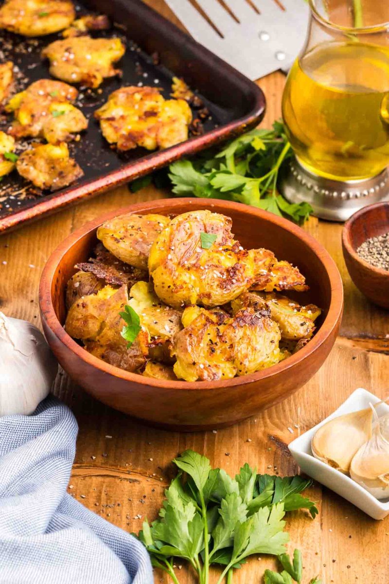 Angled view of baby potatoes smashed and baked golden brown crispy in a serving dish - Hostess At Heart
