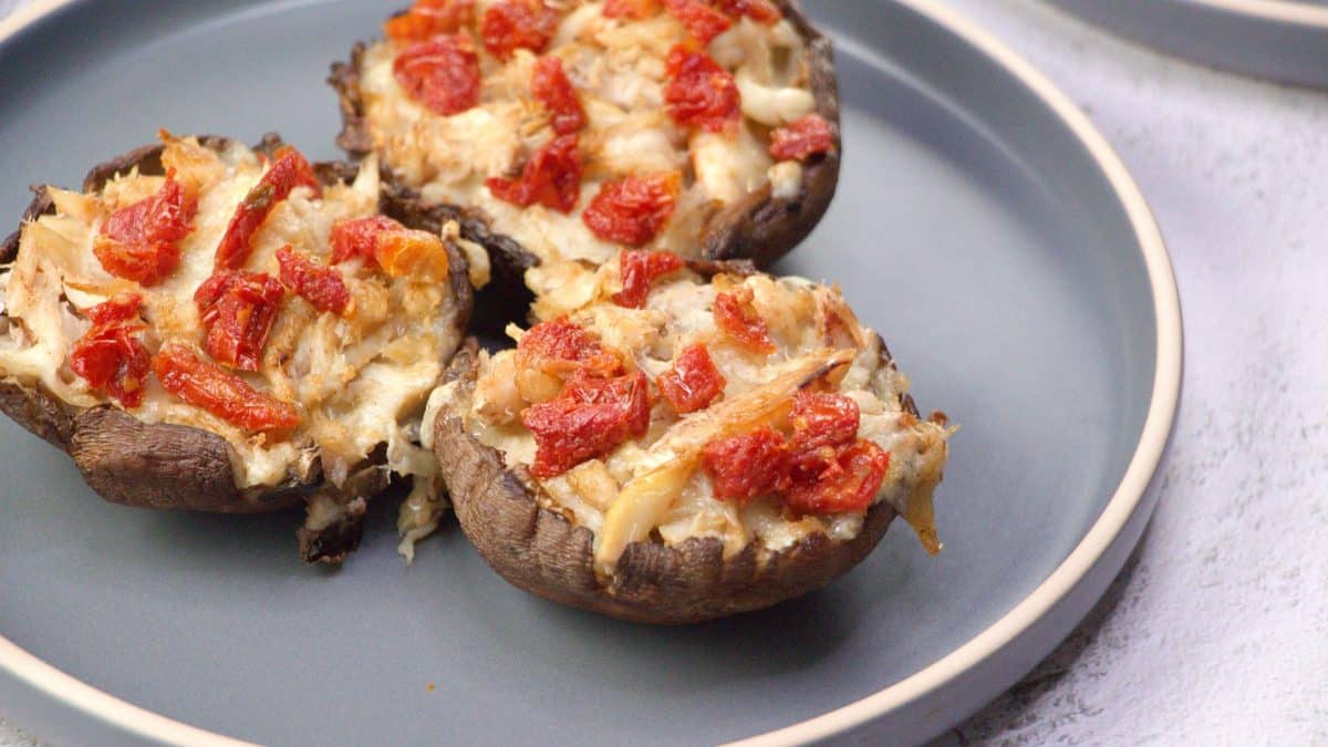 Three crab and sundried tomato stuffed portobello mushrooms on a plate - Hostess At Heart