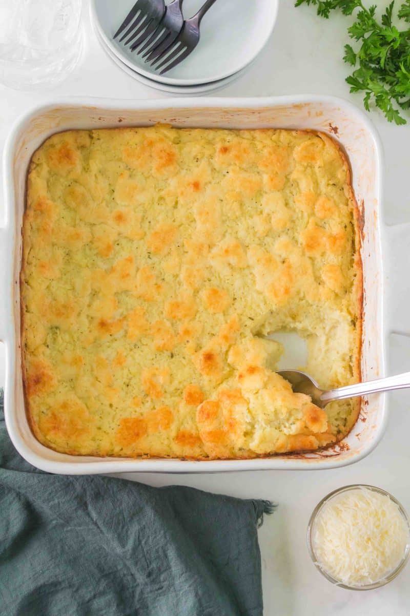 Top down view of a casserole dish containing a roasted mashed potato casserole topped with cheese. Hostess At Heart