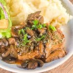 Top angled view of a juicy pork chop topped with onions and mushrooms - Hostess At Heart