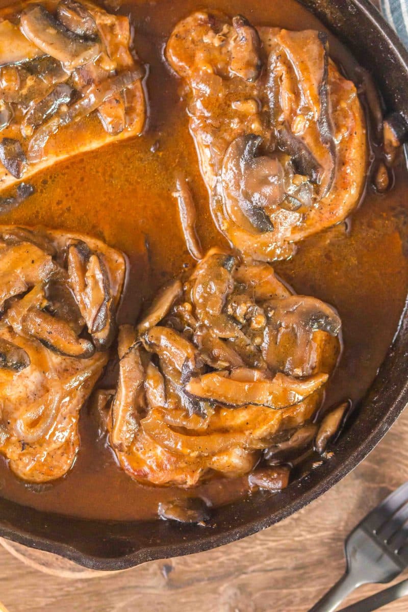Top down view of juicy boneless pork chops slathered in a mushroom onion gravy. Hostess At Heart