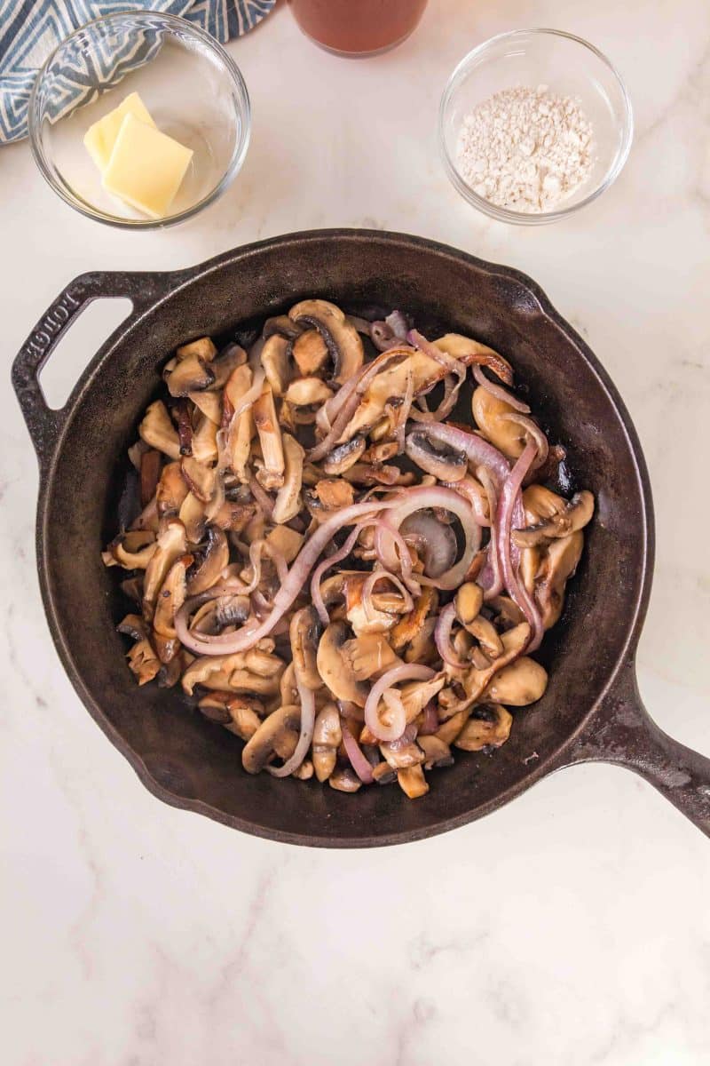 A cast iron skillet filled with cooked mushrooms and onions - Hostess At Heart