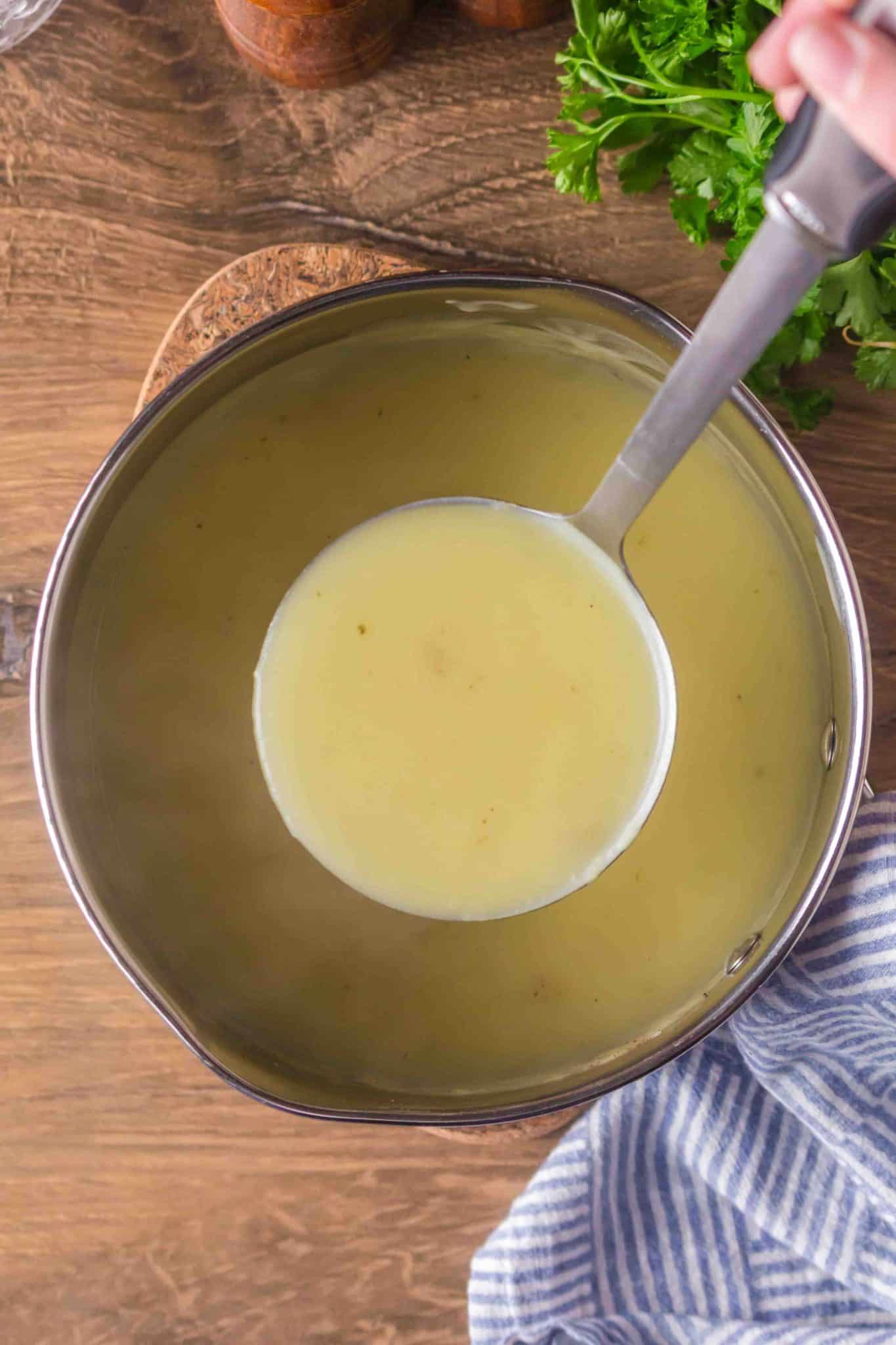 A ladle lifting chicken gravy from the pot - Hostess At Heart