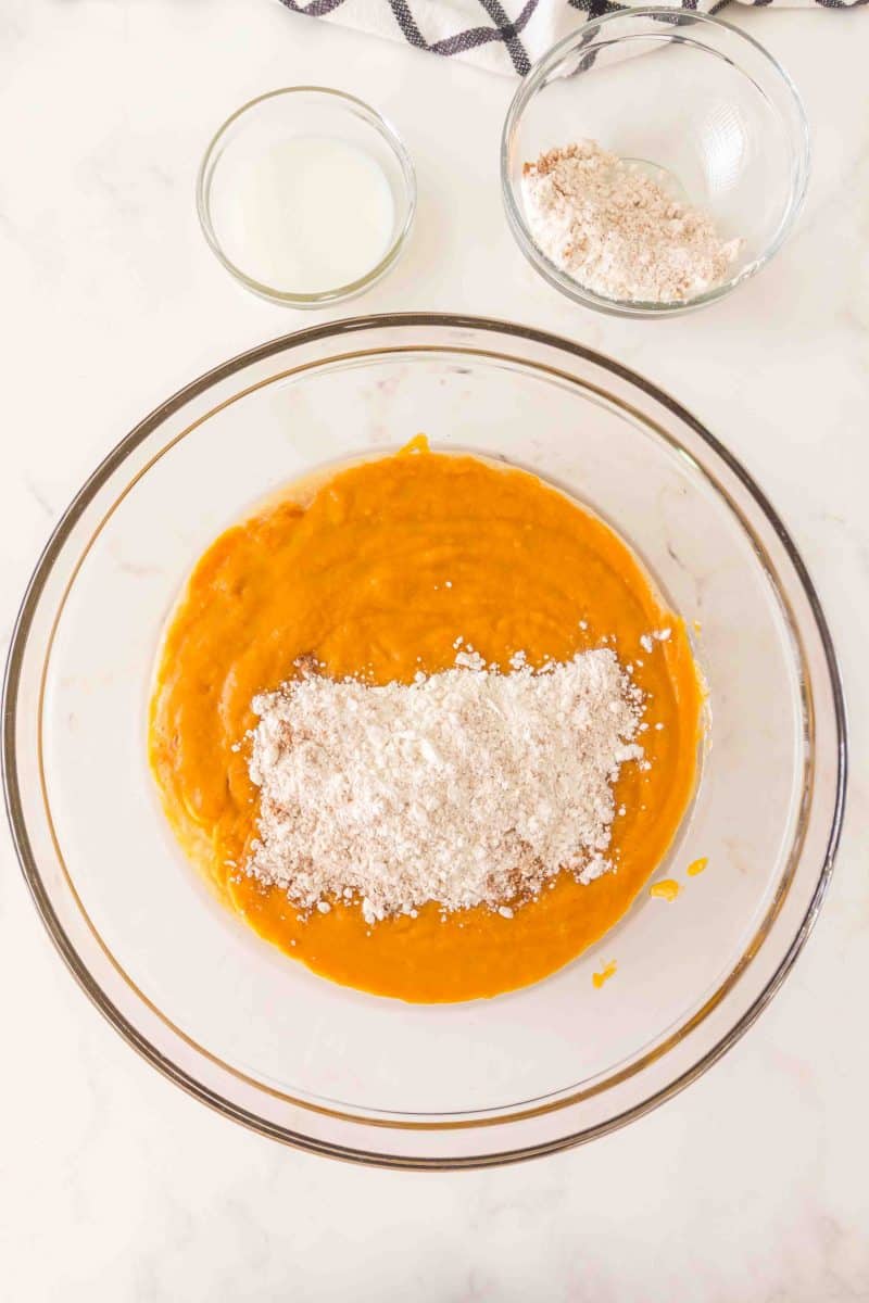 Flour added to a mixing bowl filled with creamed wet pumpkin batter ingredients. - Hostess At Heart