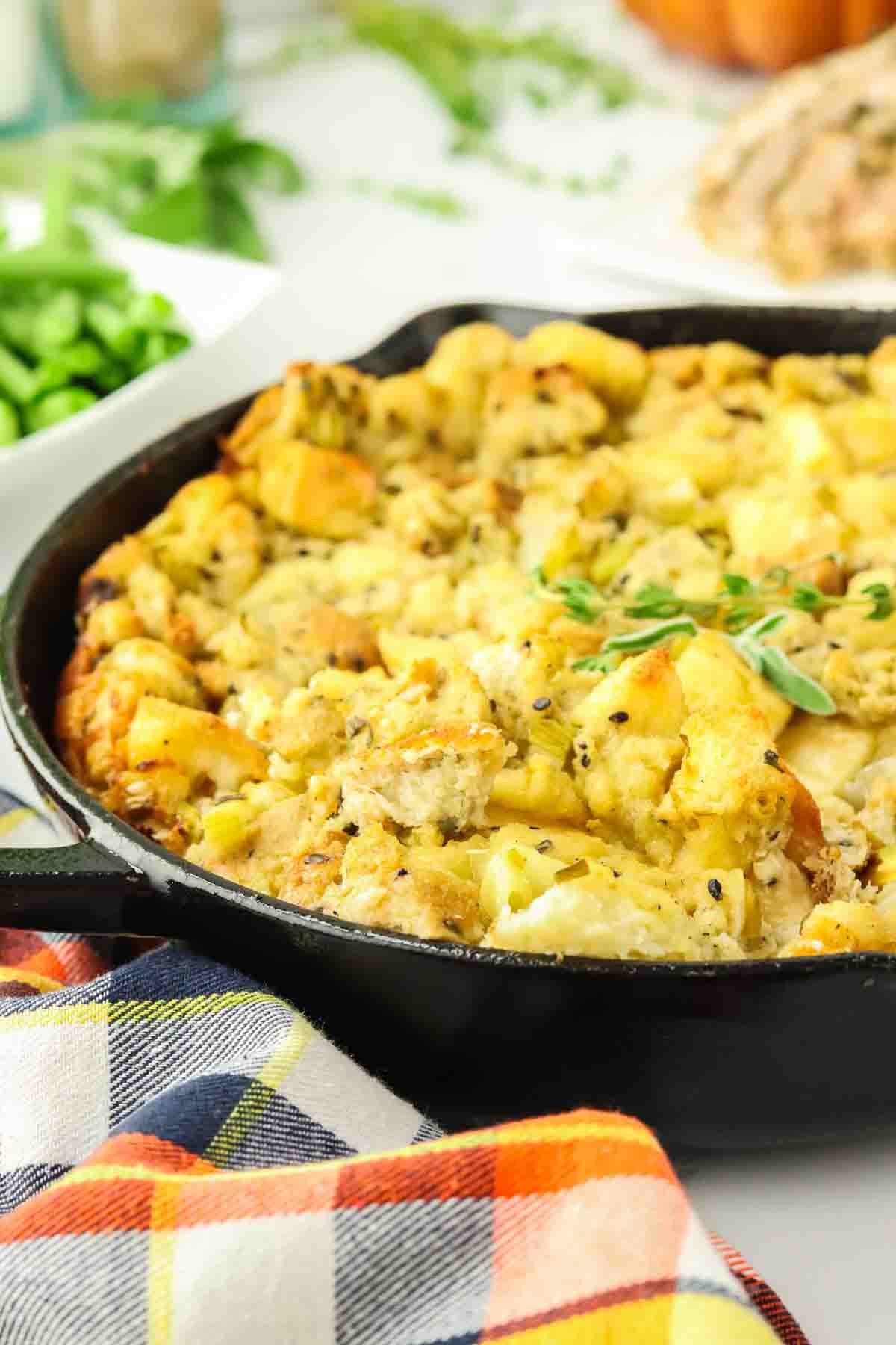 Angled view of a iron skillet filled with a fresh herb stuffing for thanksgiving - Hostess At Heart