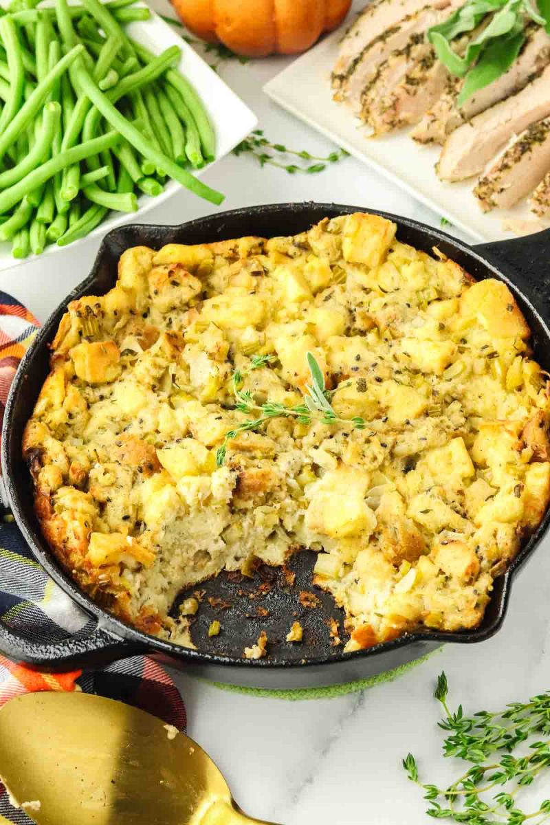 A cast iron skillet containing a stuffing with a tender interior and crispy exterior - Hostess At Heart