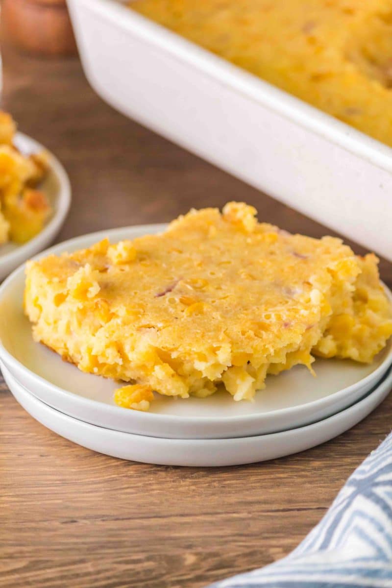 An angled view of a serving of scalloped corn casserole on a plate - Hostess At Heart