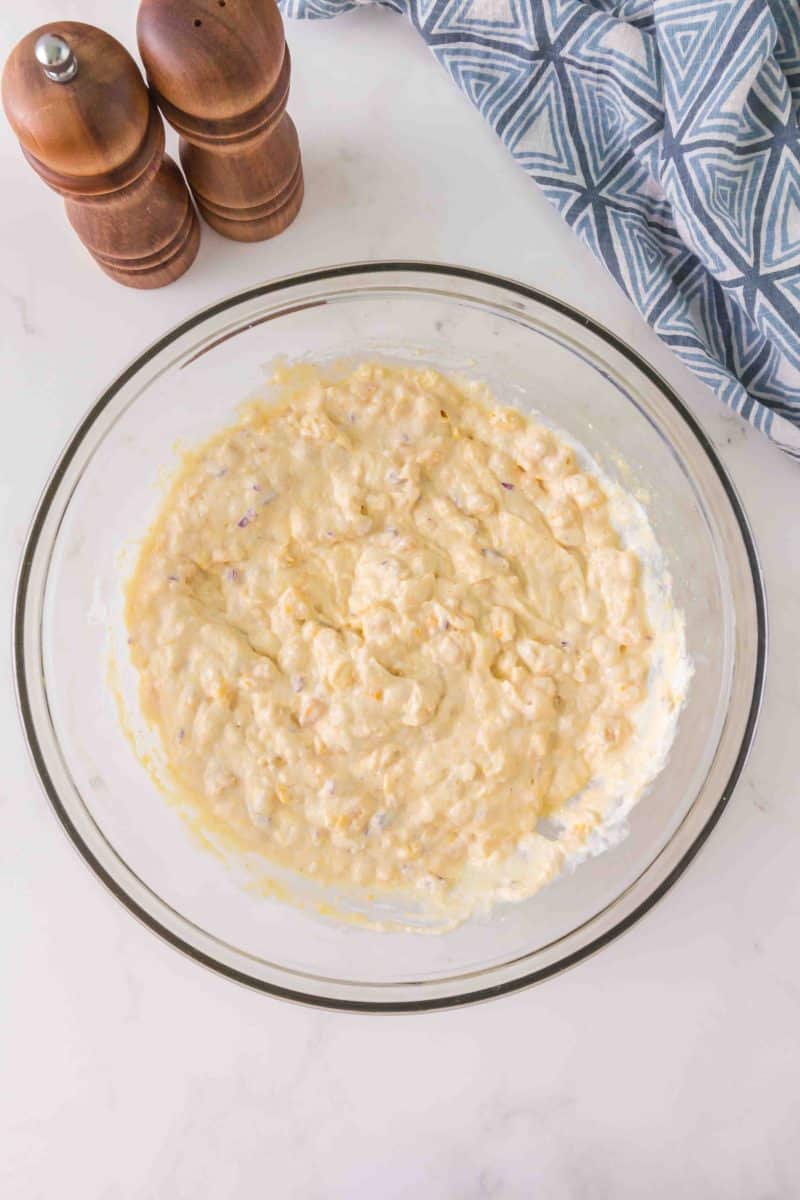 A mixing bowl filled with freshly combined easy corn casserole ingredients - Hostess At Heart