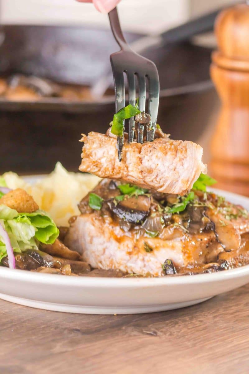 A fork filled with a slice of juicy pork chop - Hostess At Heart