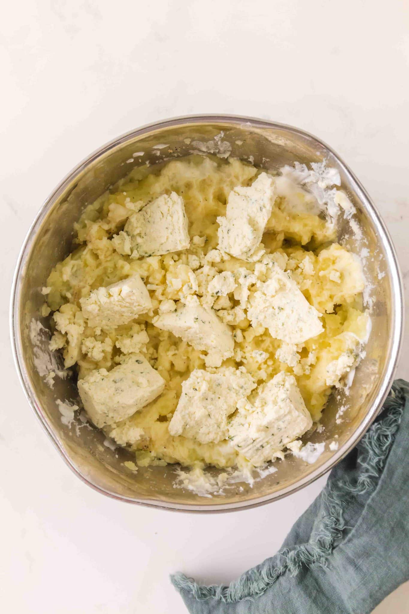 The bowl of an electric mixer filled with mashed potatoes, butter, sour cream, and boursin cheese - Hostess At Heart