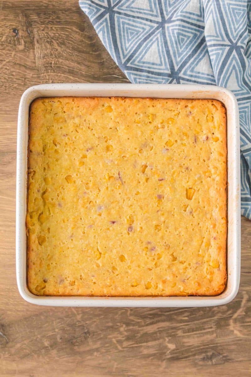 Top down image of a baking dish filled with scalloped corn casserole baked golden brown - Hostess At Heart