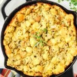 Top down view of a cast iron skillet filled with an herb stuffing - Hostess At Heart