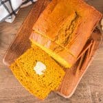 Top down view of a golden loaf of sourdough discard pumpkin bread. The front two slices have been fanned in front of the loaf - Hostess At Heart