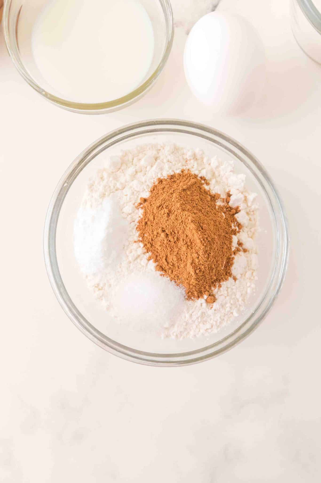 A mixing bowl filled with flour, baking powder, salt, baking soda, and pumpkin pie spice - Hostess At Heart