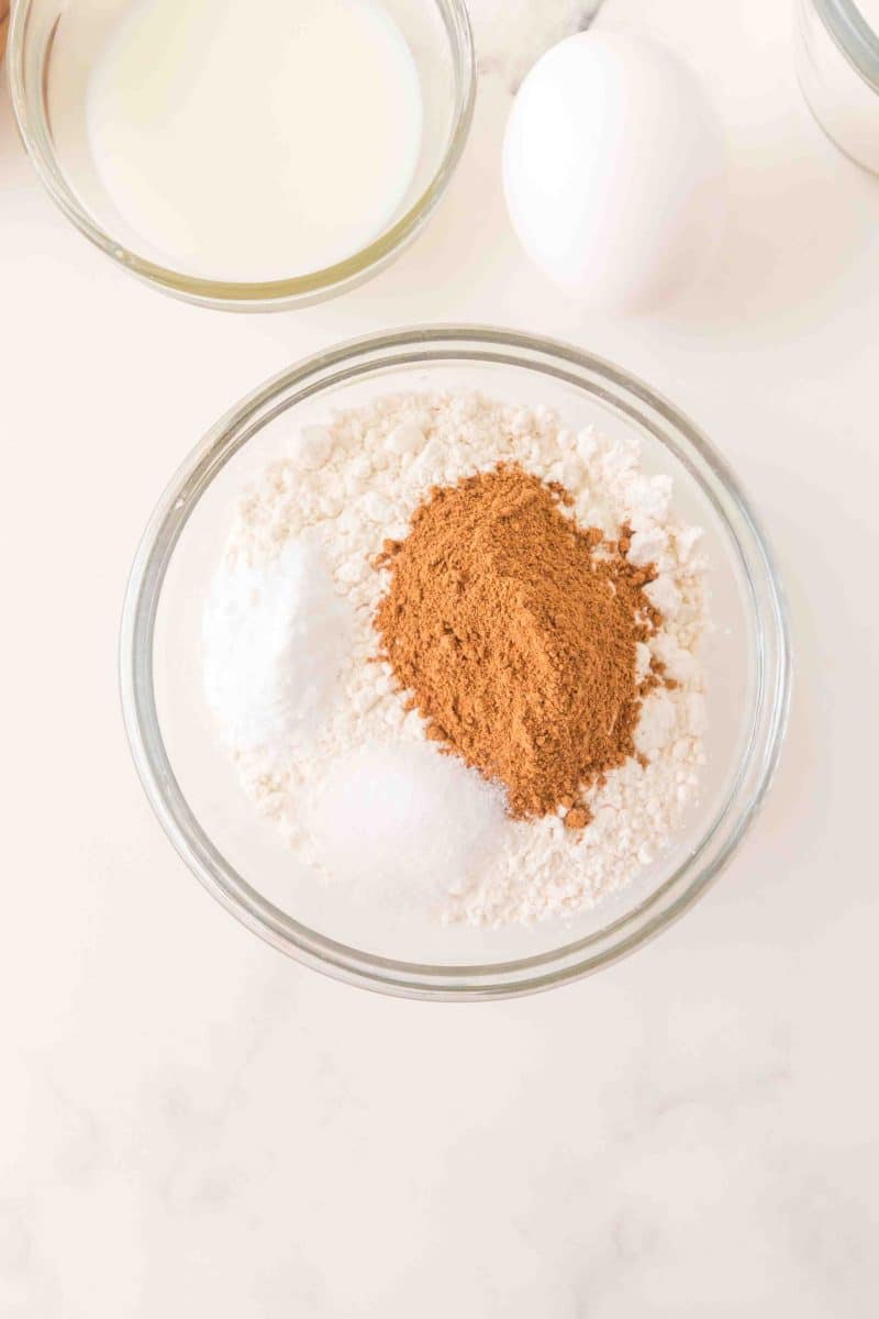 A mixing bowl filled with flour, baking powder, salt, baking soda, and pumpkin pie spice - Hostess At Heart