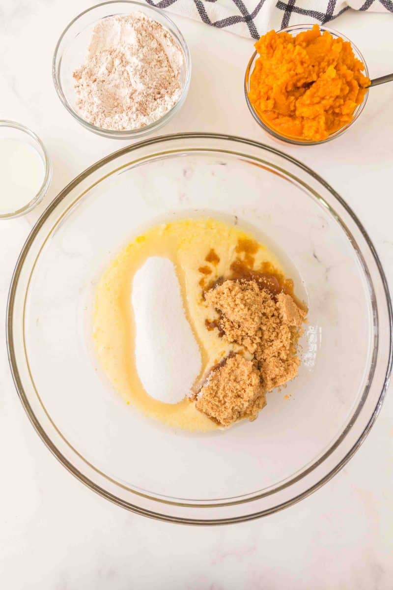 Top down view of adding brown sugar, white sugar, and vanilla to a bowl containing a mixture of egg, sourdough starter, and oil. Hostess At Heart