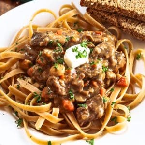 Closeup angle of a plate of pasta topped with a rich beef stroganof sauce with carrots. Hostess At Heart