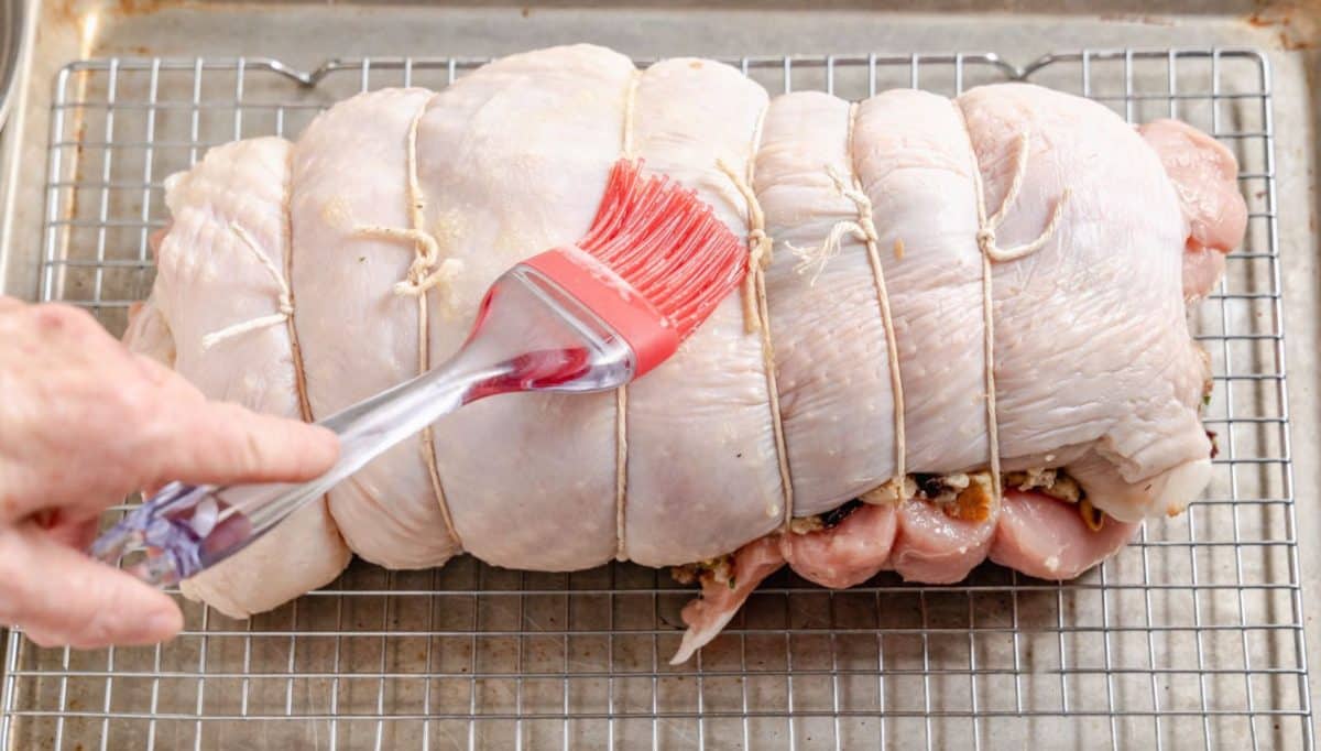 A turkey breast stuffed roll that's being basted with butter.