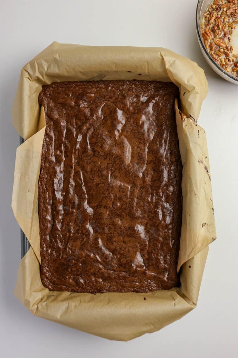 Partially baked brownie layer with set edges and soft center in baking pan - Hostess At Heart