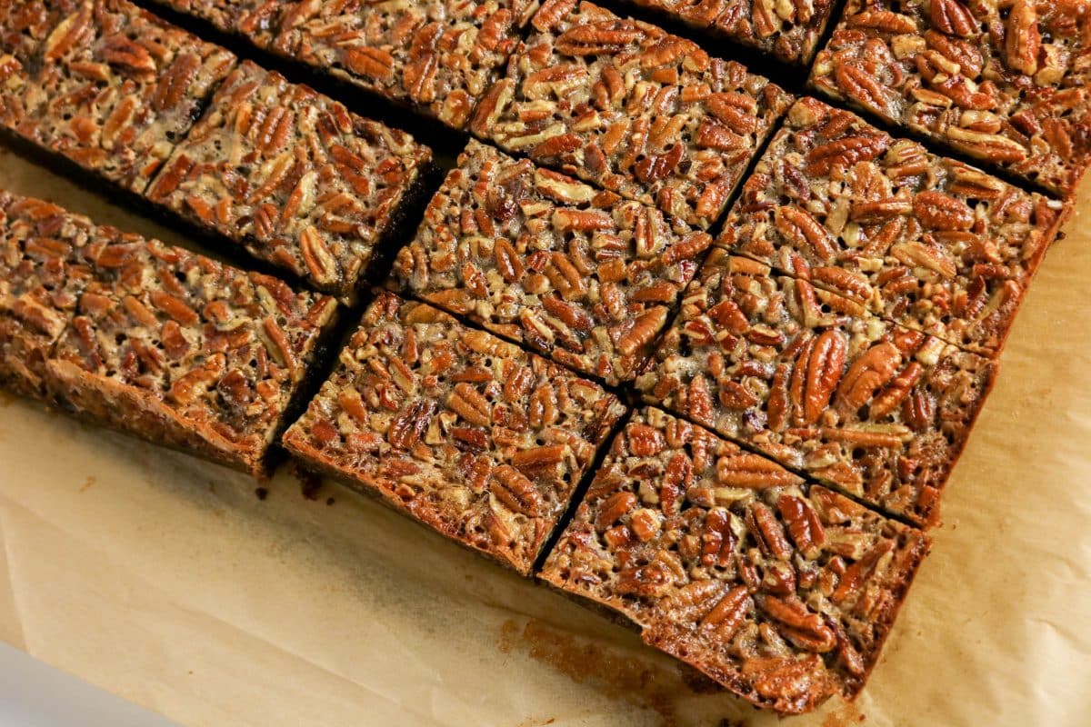 Top down view of cut squares of pecan pie brownies on parchment paper - Hostess At Heart