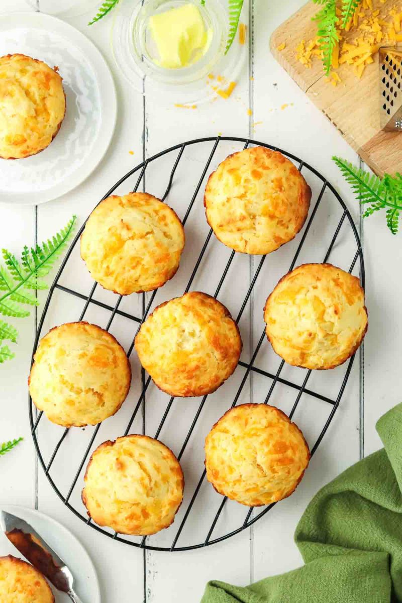 Top down view of freshly baked cheddar cheese muffins fresh from the oven and cooling on a baking rack - Hostess At Heart
