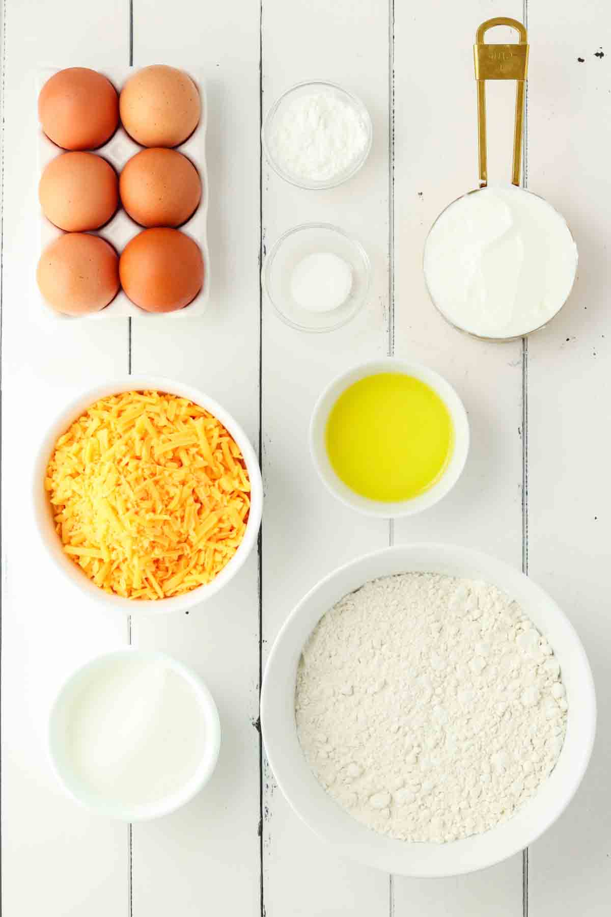 Ingredients for cheddar cheese muffins including flour, cheddar cheese, eggs, and yogurt - Hostess At Heart